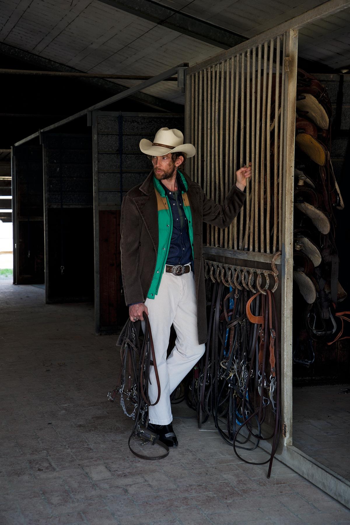 Soprabito doppiopetto in fustagno, Boglioli; gilet in piumino e pelle, Woolrich; camicia in denim; Levi’s; serafino in cotone, Ovs; pantaloni in velluto, Jeckerson; stivali texani, Sonora; cintura con fibbia, Vintage; cappello, Stetson.