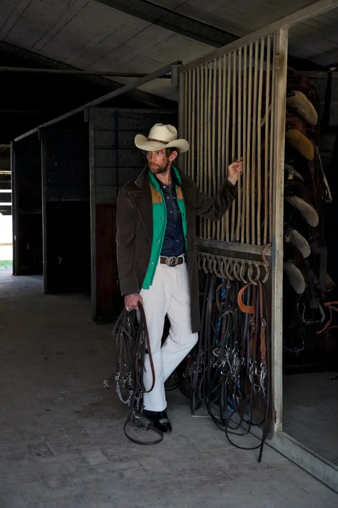 Soprabito doppiopetto in fustagno, Boglioli; gilet in piumino e pelle, Woolrich; camicia in denim; Levi’s; serafino in cotone, Ovs; pantaloni in velluto, Jeckerson; stivali texani, Sonora; cintura con fibbia, Vintage; cappello, Stetson.