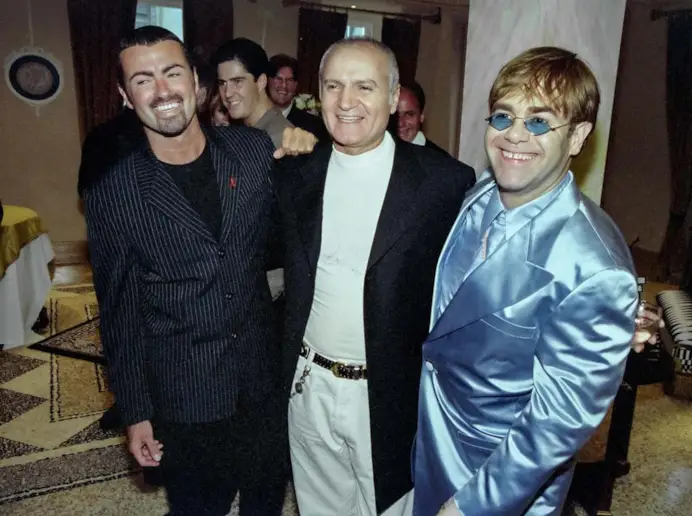 COPYRIGHT © Peter Macdiarmid - Image only for editorial use in connection with Arches London Bridge Gianni Versace Retrospective Exhibition. London, UK. 14/06/1995 George Michael (L) stands with Gianni Versace and Elton John (R) at a party to launch Versace's book 'Men Without Ties'. Photograph Peter Macdiarmid.