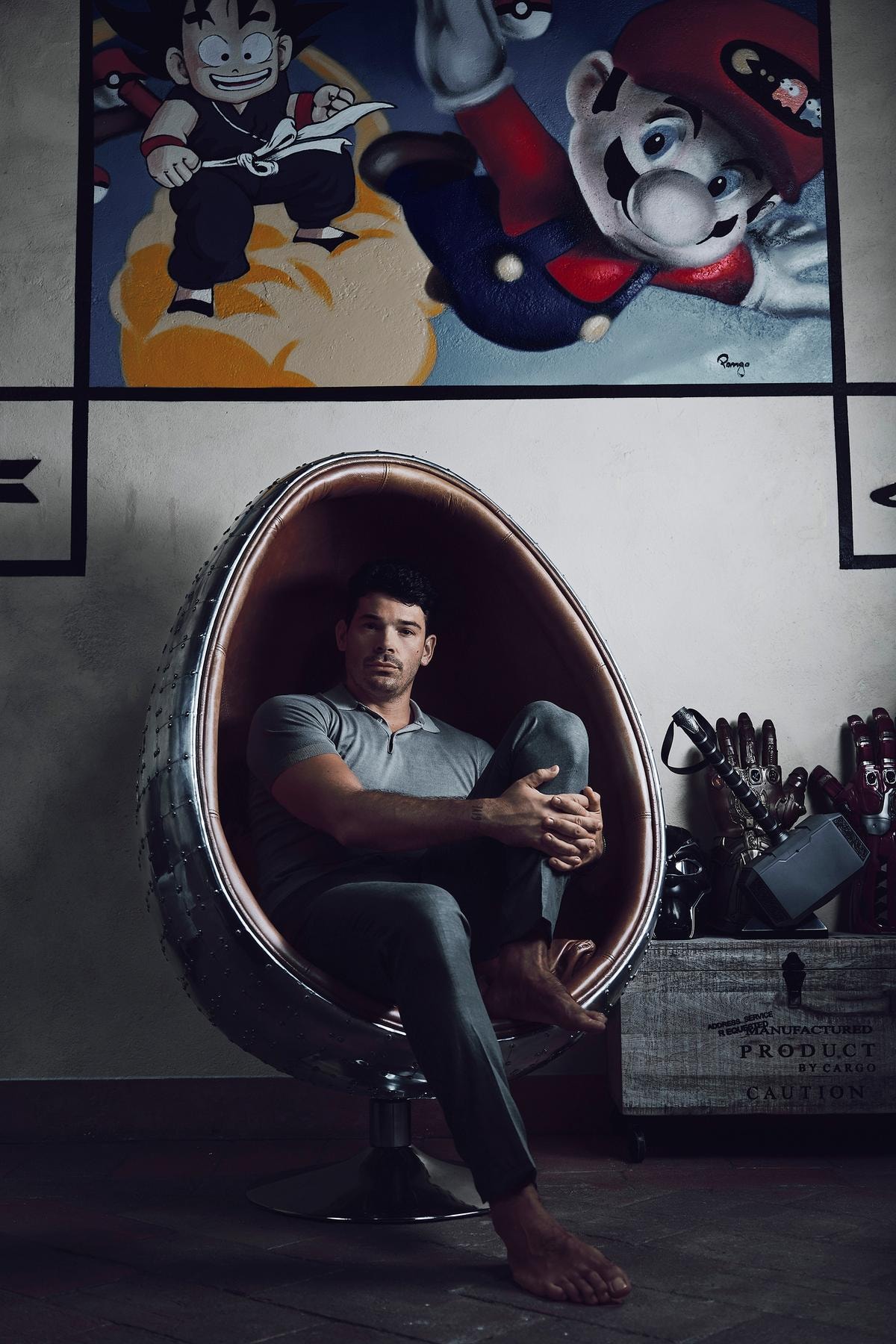 Nella foto Cristian Trio indossa  una polo e pantaloni  di Noi, alle sue  spalle l’opera Nerd Paradise di Pongo.