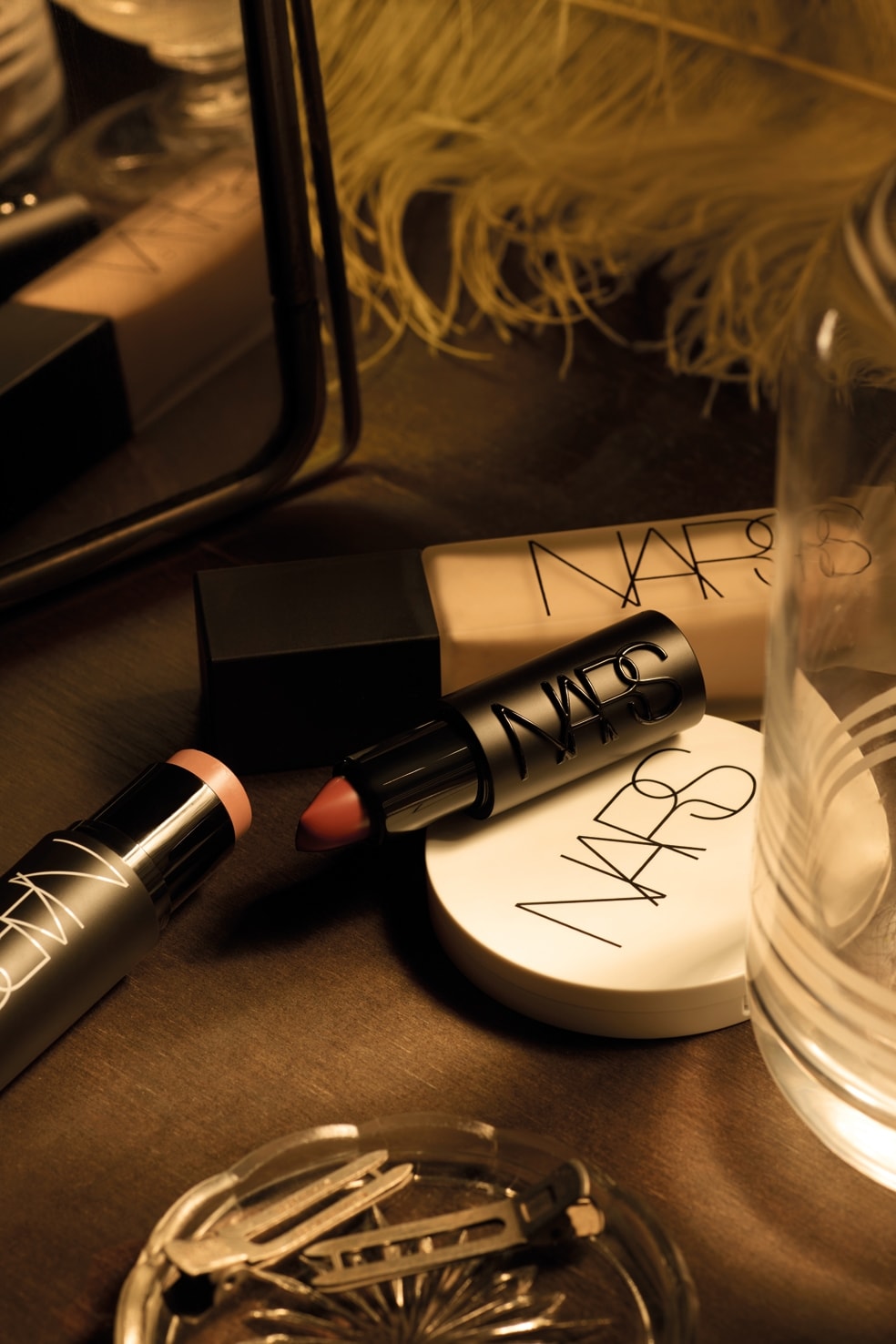Dall’alto in senso orario, fondotinta Natural matte a lunga tenuta nella tonalità Mont blanc,  rossetto satinato Explicit lipstick nella nuance No rules, illuminante viso Luminizing powder nel colore Electra e stick multiuso The multiple per occhi, labbra e guance nella nuance Behave, tutto di Nars cosmetics (ph Sonia Marin)