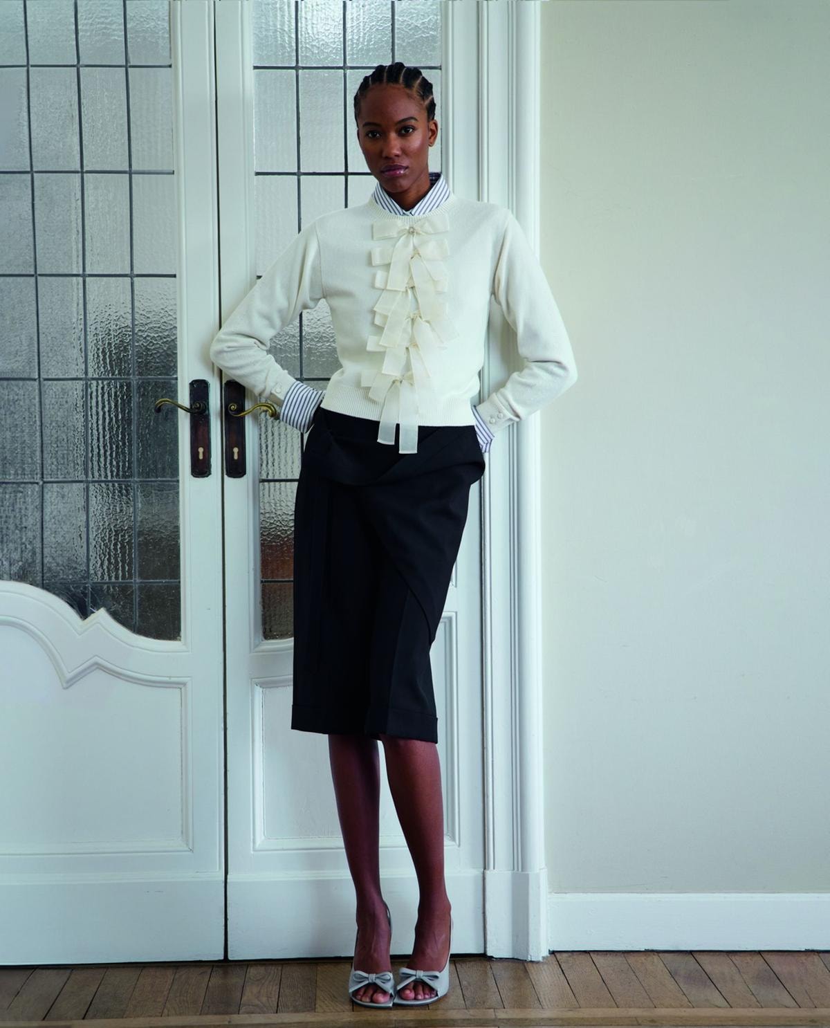 Pull in lana e cashmere, camicia, bermuda drappeggiati e sandali, tutto di Dior.