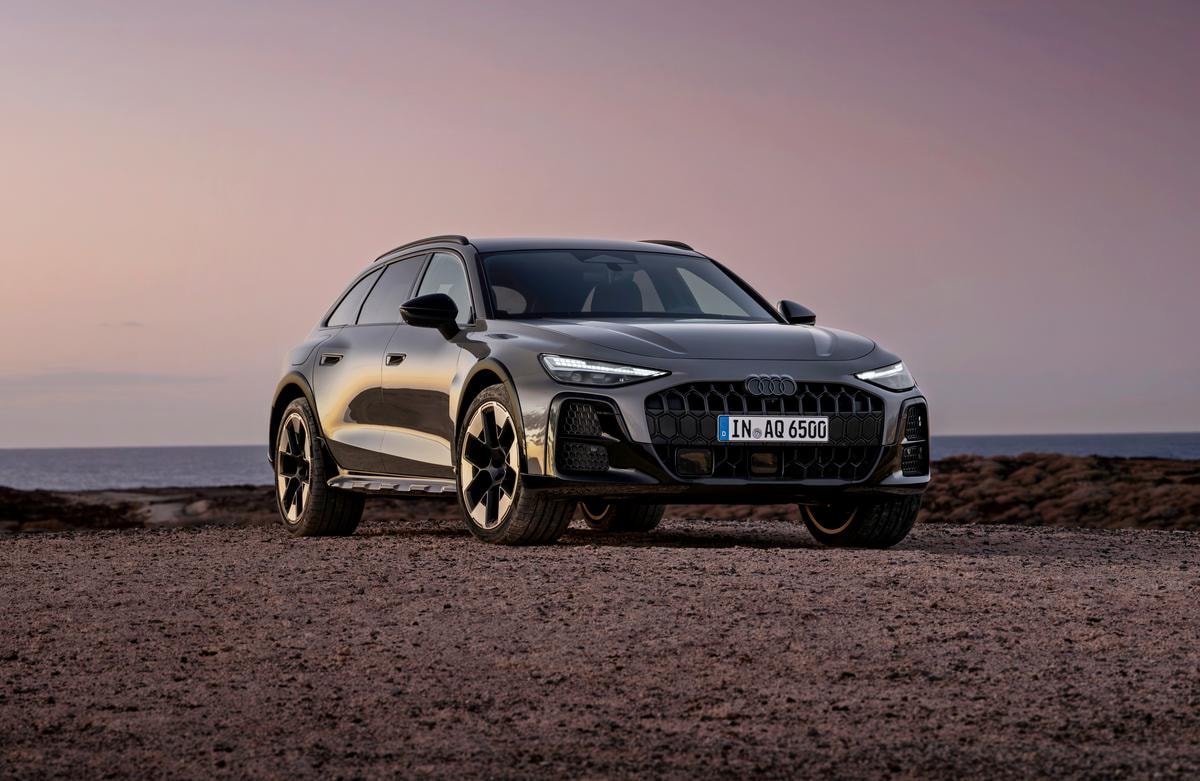 ¾ Front view of the Audi A6 allroad (plateau grey metallic) against a calm sea horizon at dusk.