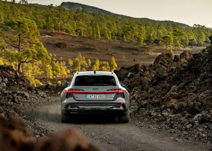 Rear view of the Audi A6 allroad (plateau grey metallic) on a narrow gravel track in volcanic terrain.